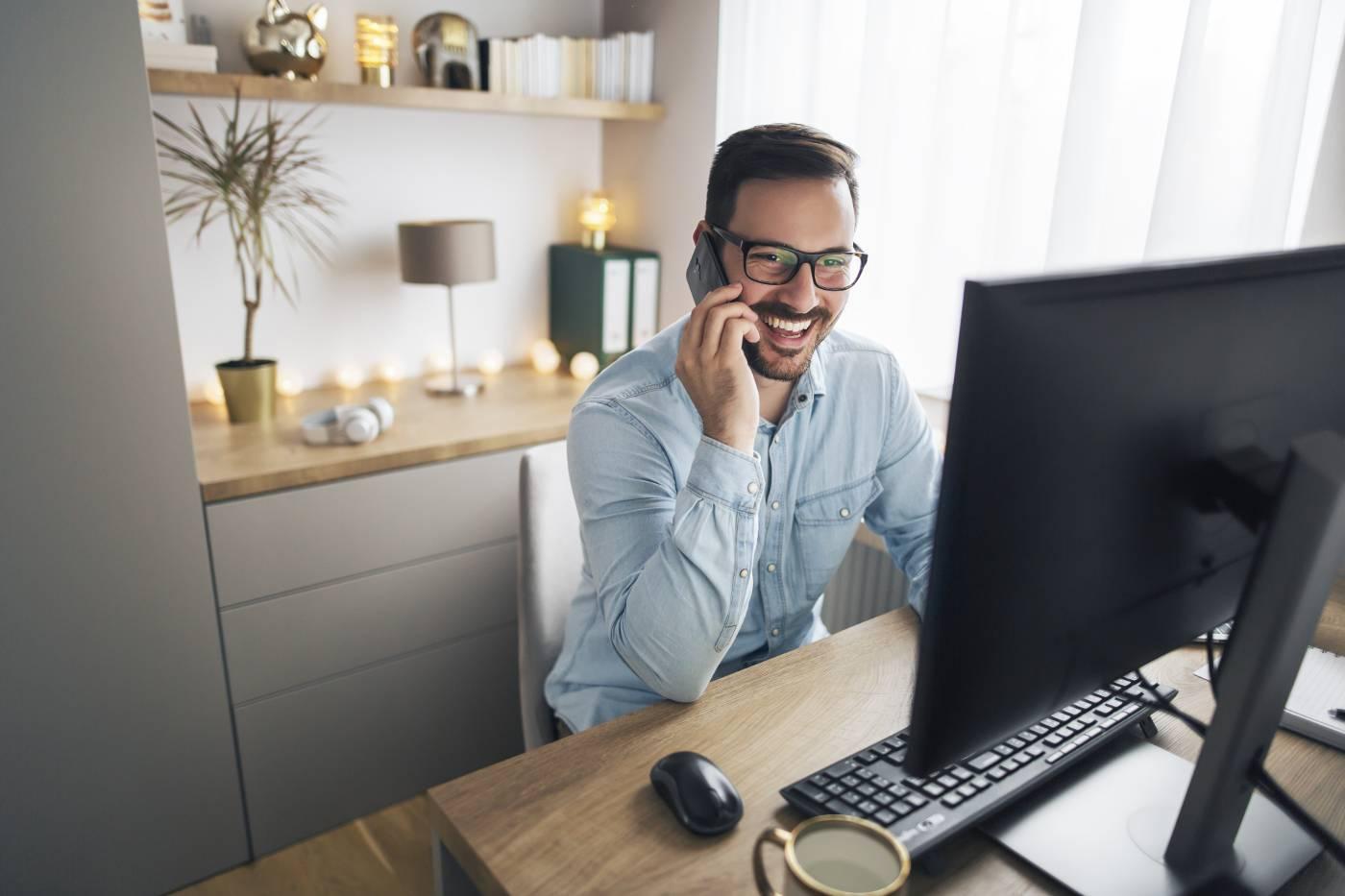 Man working from home on computer while on phone