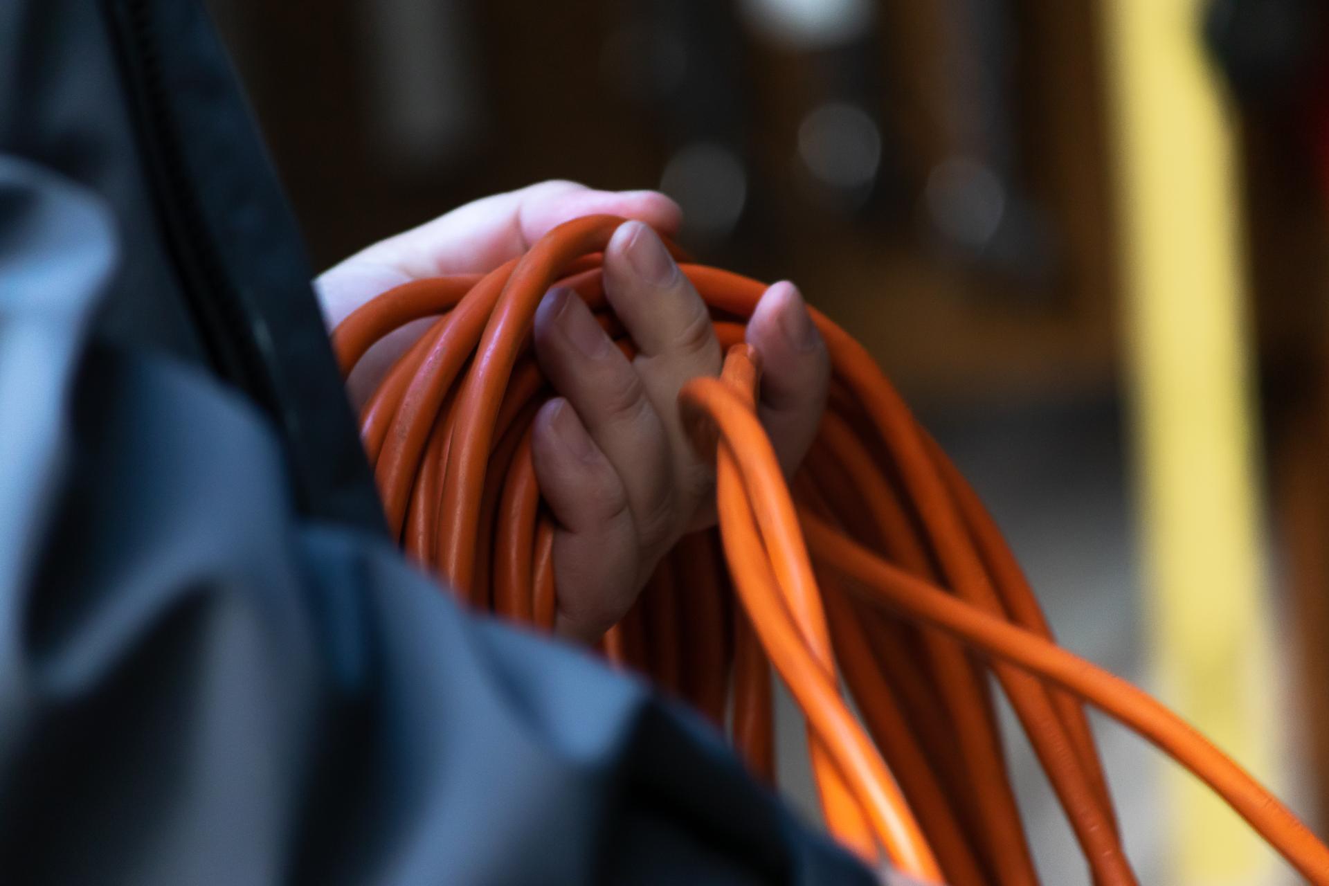 man holding a long extension cord in left hand