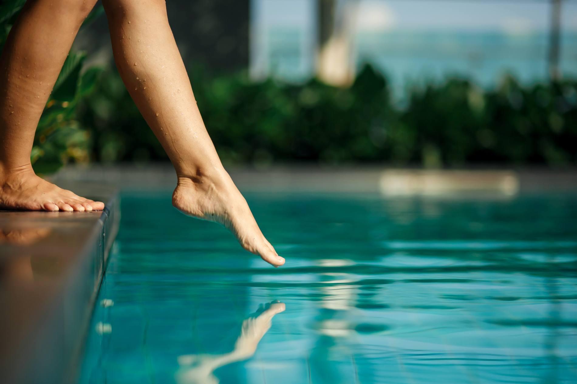 woman dipping toes in pool