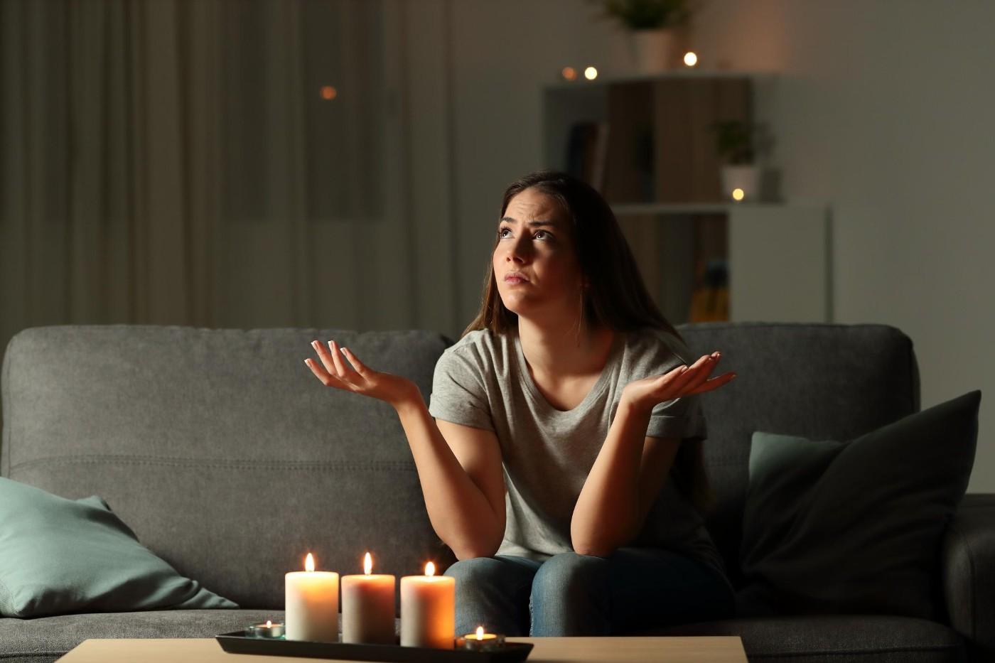 woman sitting on couch with lit candles during outage