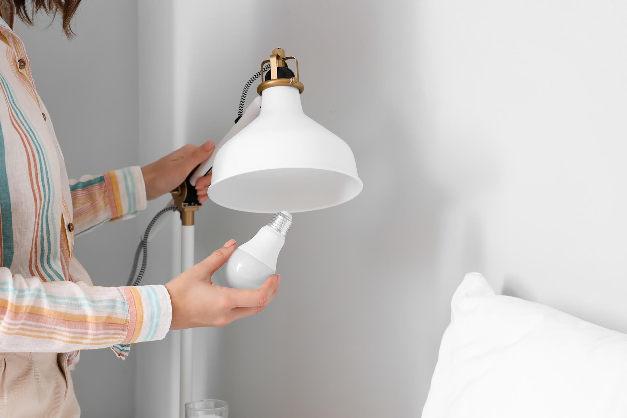 Woman installing LED bulb in a fixture