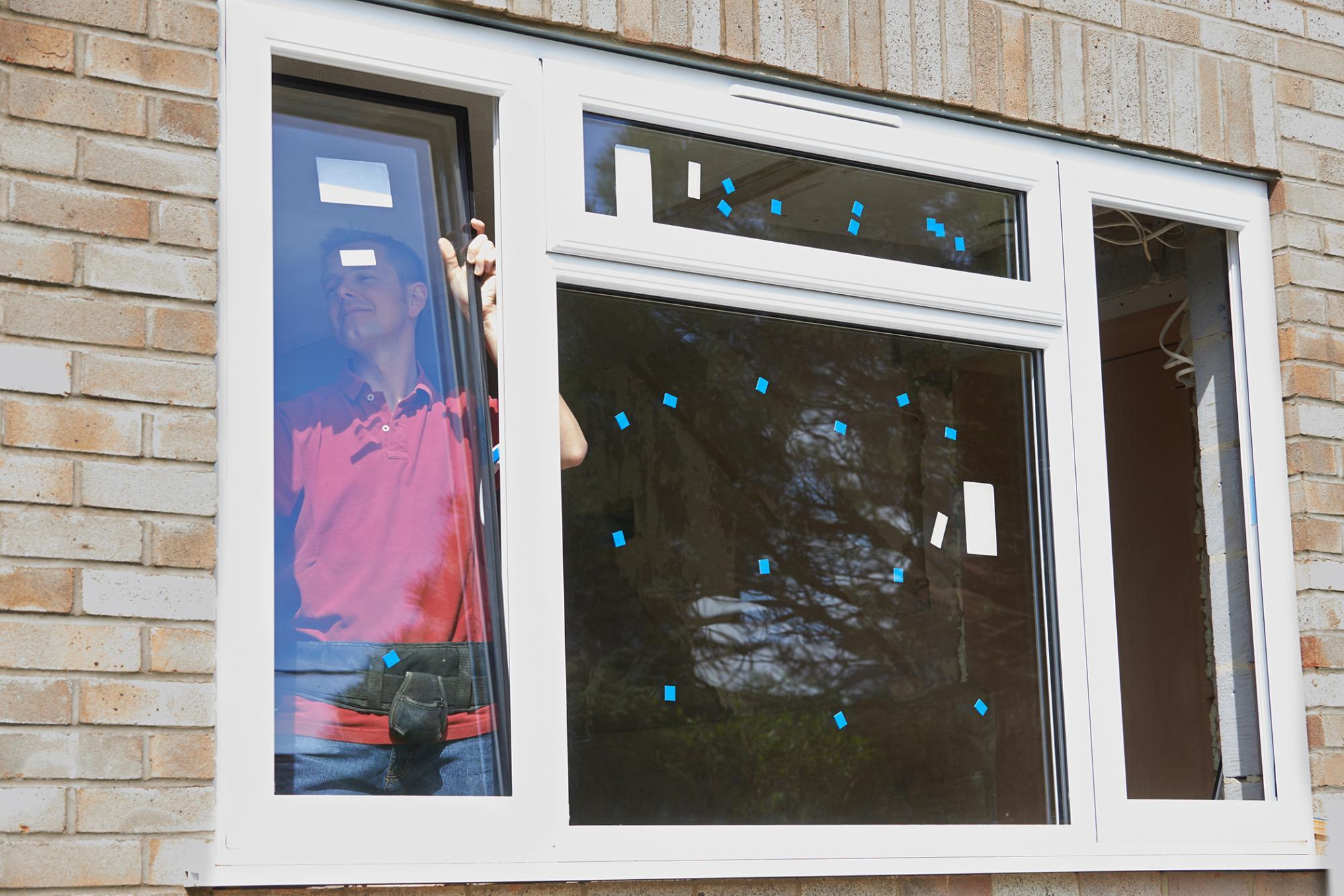 View from outside of a home with a contractor that can be seen through a window that he is installing