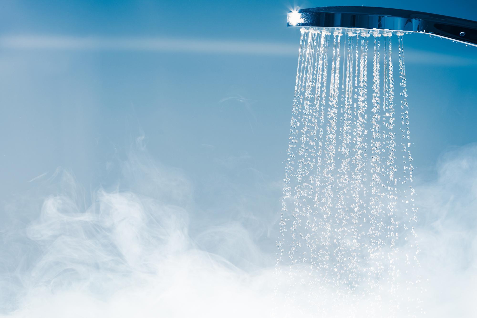 Hot water coming out of a shower head with steam at the bottom flowing up