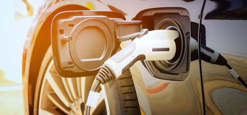 Electric vehicle zoomed in on charging port with a charger plugged into it
