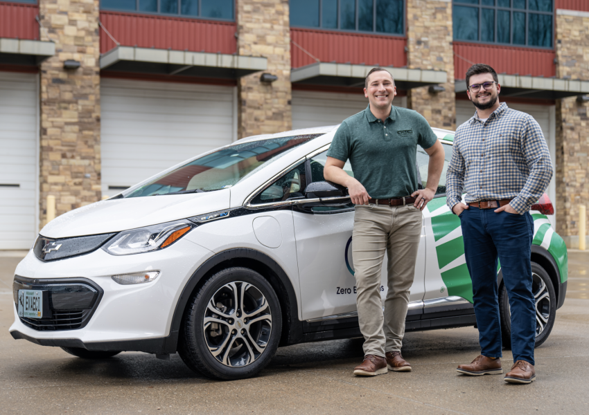 guys leaning against electric vehicle